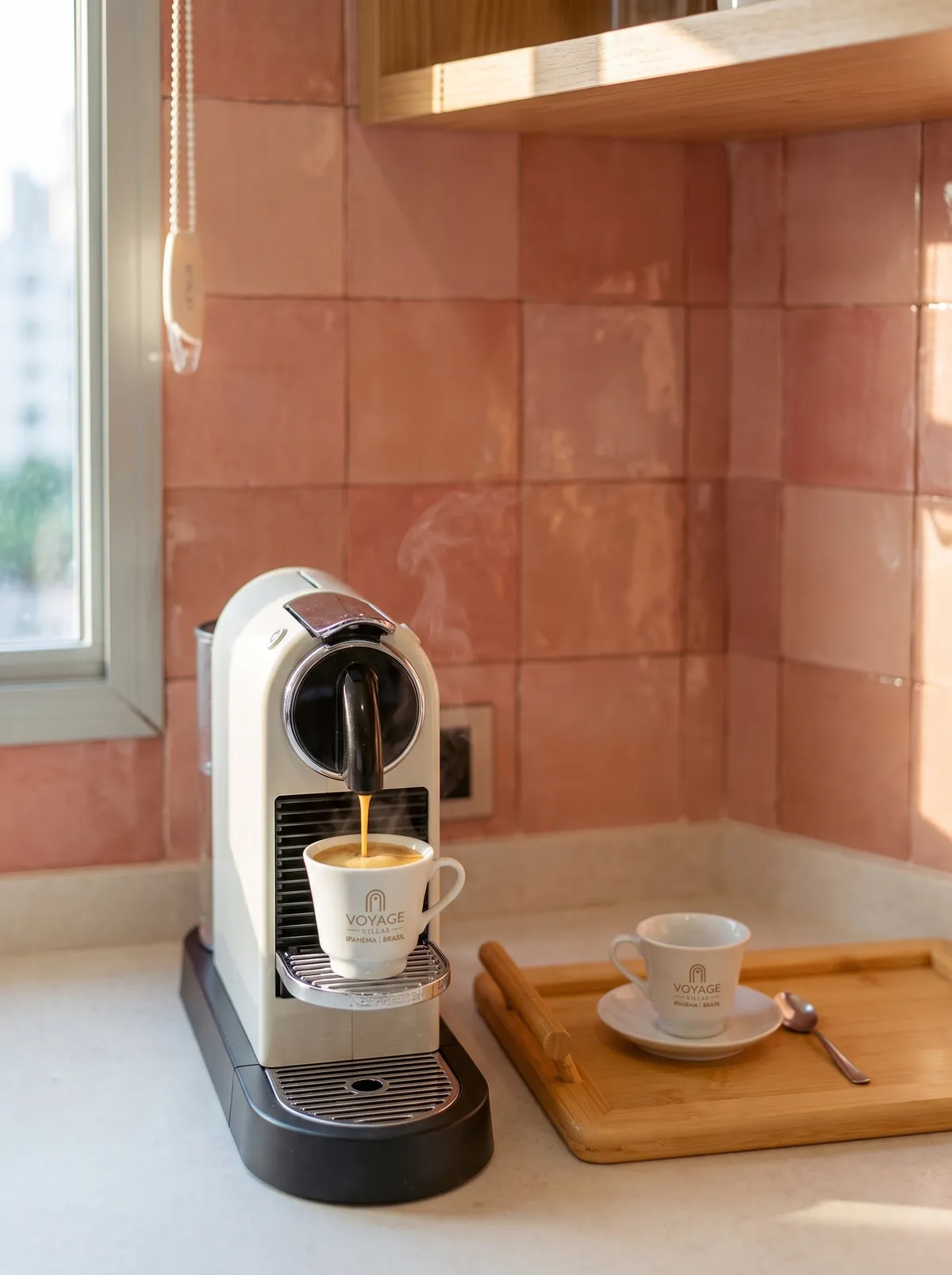 Café na bancada da cozinha, com azulejo rosa e máquina de café