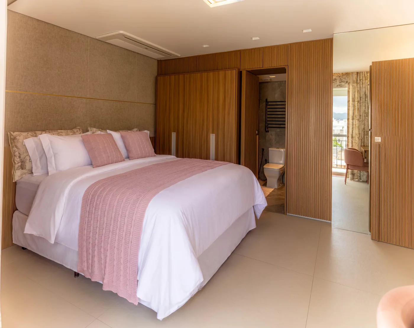 Quarto do apartamento com roupa de cama rosa
